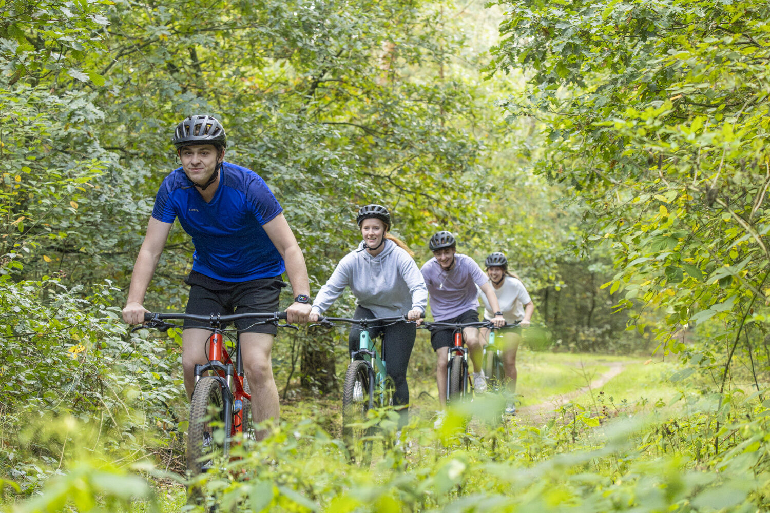 1 man en 3 vrouwen op gehuurde mountainbikes in het bos op de Veluwe